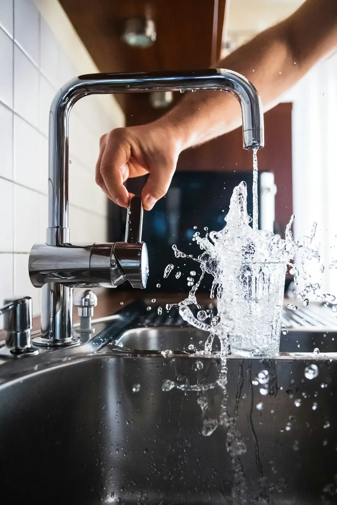 Glass being filled with fresh water at a kitchen tap